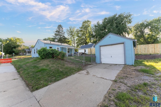 view of front of house with driveway, a detached garage, an outbuilding, fence, and a front lawn