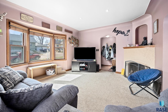 carpeted living area with a fireplace and baseboards