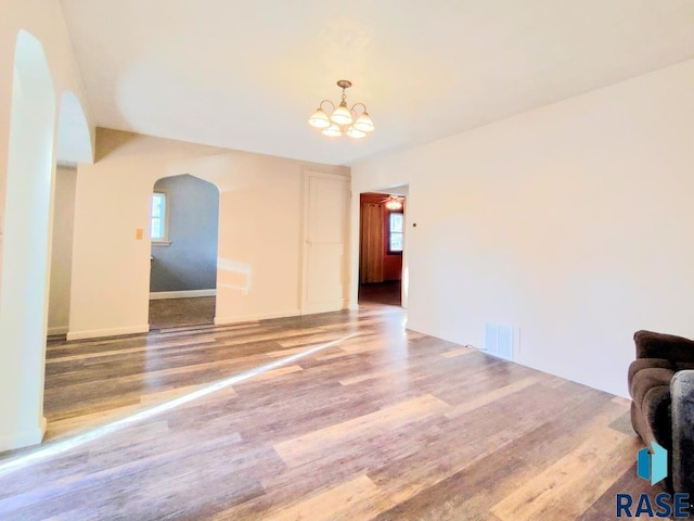 interior space with arched walkways, a healthy amount of sunlight, visible vents, and wood finished floors