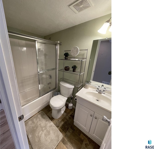 full bathroom with visible vents, bath / shower combo with glass door, toilet, a textured ceiling, and vanity