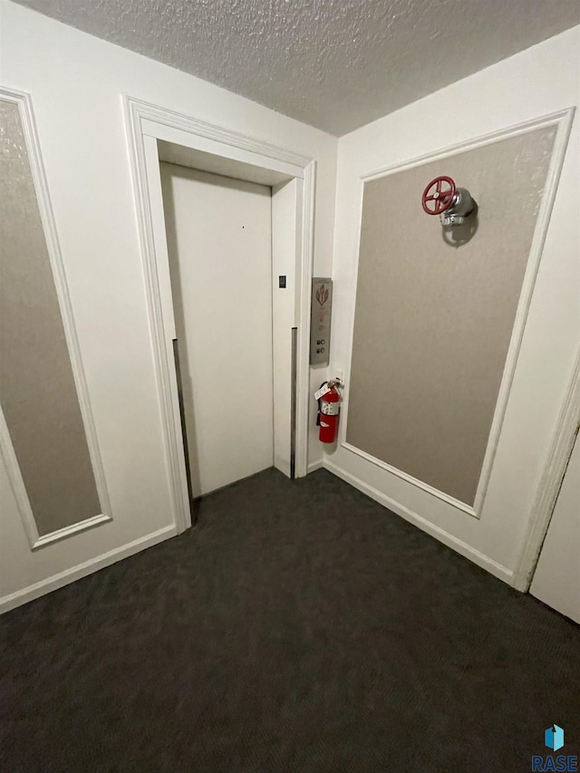 interior space featuring dark carpet and a textured ceiling