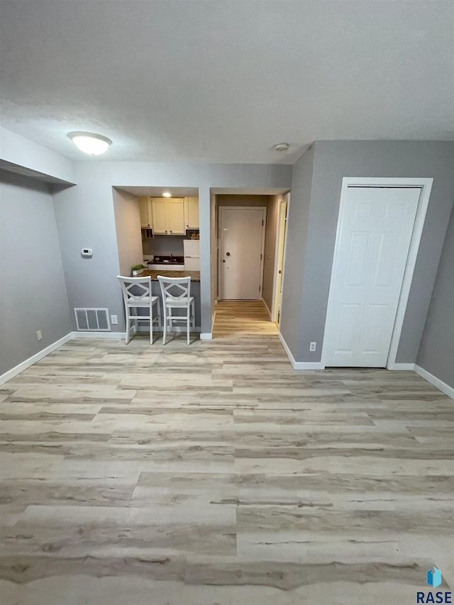 kitchen with light wood-type flooring, light brown cabinets, visible vents, and baseboards