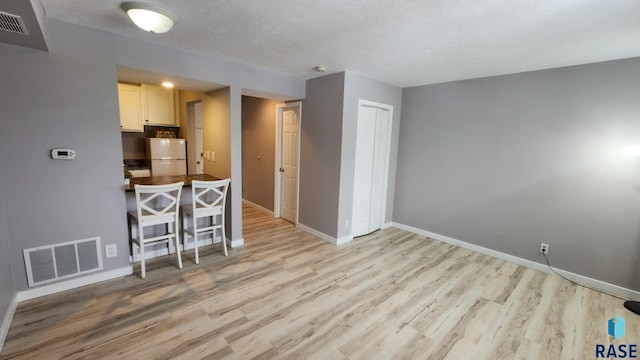 kitchen with light wood finished floors, baseboards, visible vents, and freestanding refrigerator