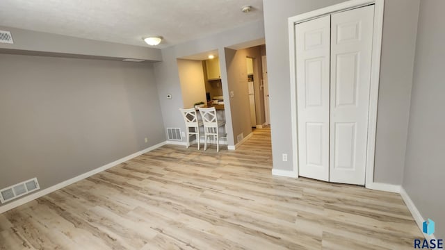 unfurnished room featuring light wood-type flooring, visible vents, and baseboards