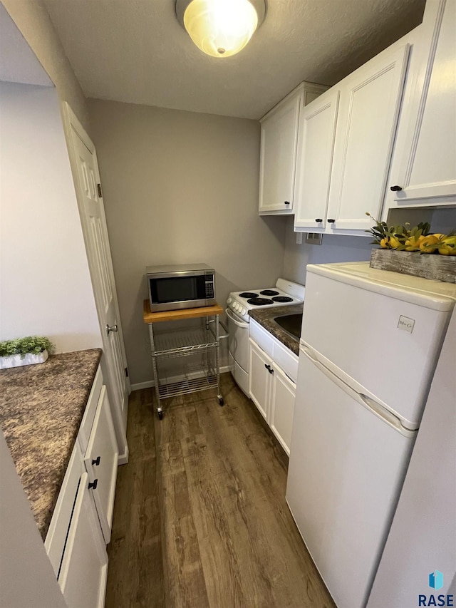 kitchen featuring dark countertops, white appliances, dark wood-style floors, and white cabinetry