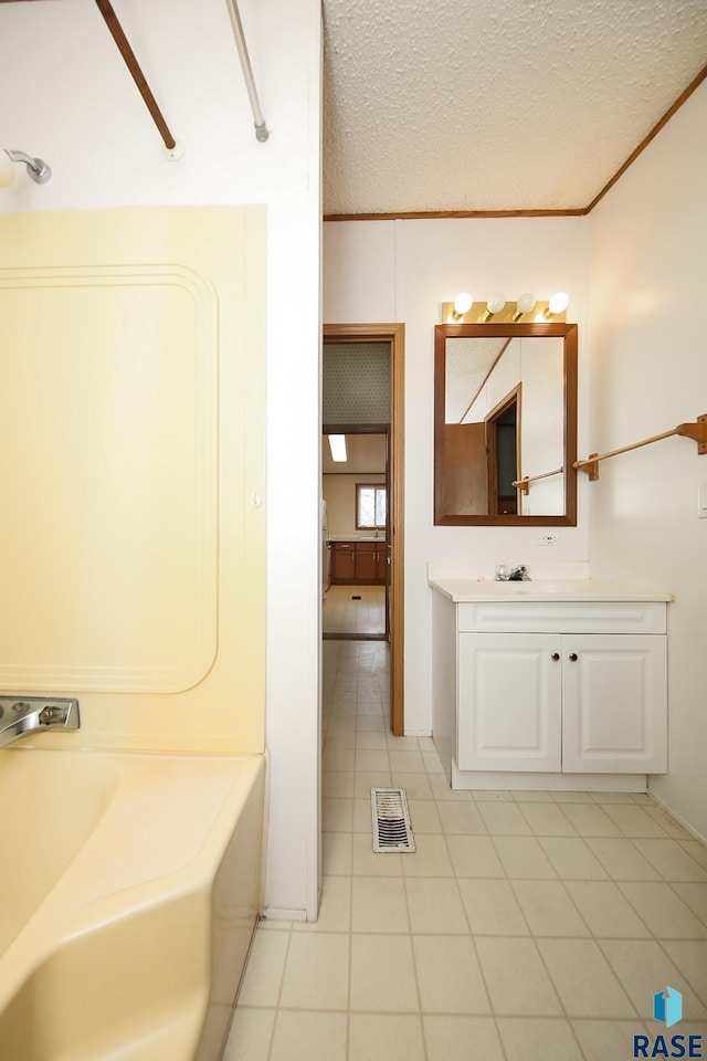 full bathroom featuring a bathtub, crown molding, visible vents, a textured ceiling, and vanity