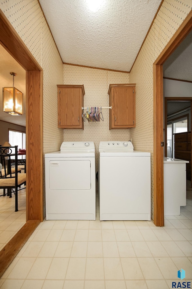 laundry room featuring cabinet space, ornamental molding, washing machine and dryer, a textured ceiling, and wallpapered walls