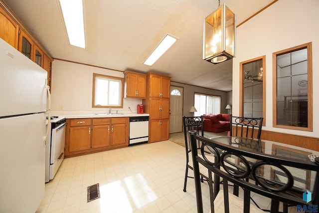 kitchen with white appliances, a sink, visible vents, light countertops, and brown cabinets