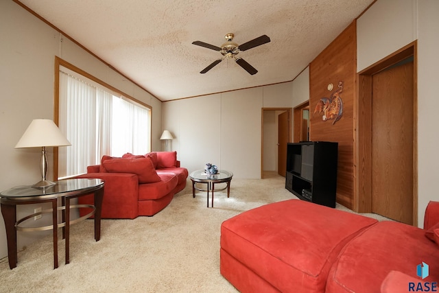 living area featuring light carpet, wood walls, a textured ceiling, and a ceiling fan