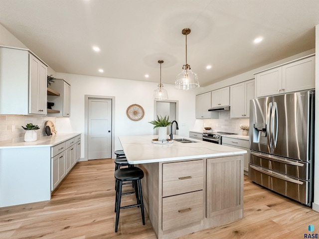 kitchen featuring light countertops, appliances with stainless steel finishes, a kitchen island with sink, a sink, and white cabinetry