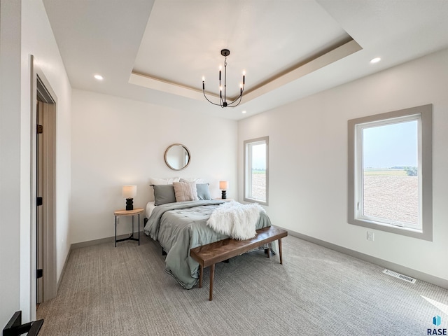 bedroom with carpet flooring, visible vents, baseboards, a raised ceiling, and an inviting chandelier