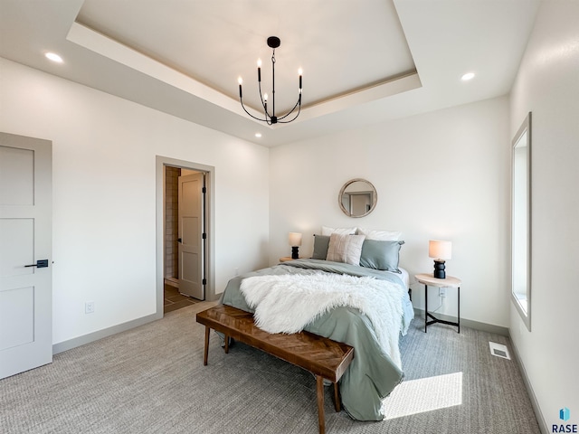 bedroom featuring light carpet, visible vents, baseboards, a tray ceiling, and a chandelier