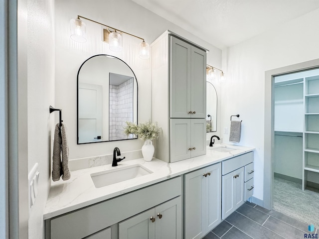 bathroom with tile patterned floors, a sink, a spacious closet, and double vanity