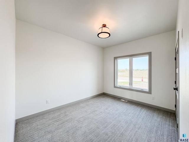 unfurnished room with visible vents, light colored carpet, and baseboards