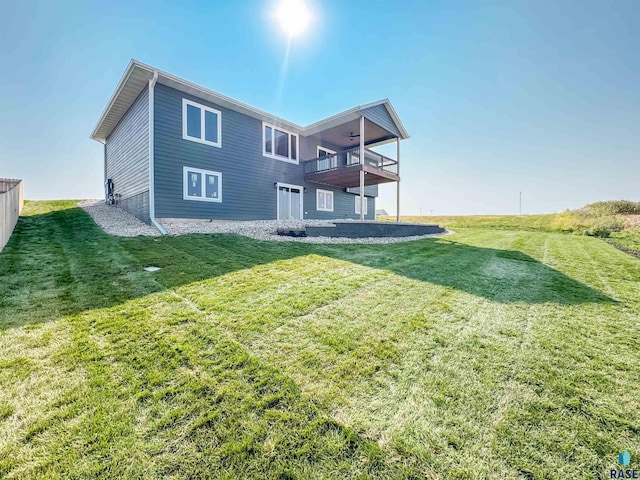 rear view of house with a balcony, fence, and a lawn