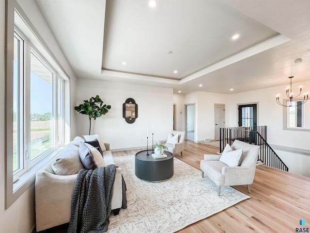 living area featuring light wood-style flooring, a raised ceiling, and a wealth of natural light