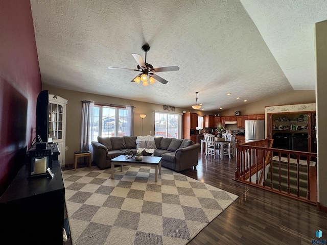 living area with vaulted ceiling, a textured ceiling, light wood-type flooring, and a ceiling fan