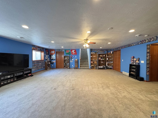 unfurnished living room with a textured ceiling, carpet floors, and stairway