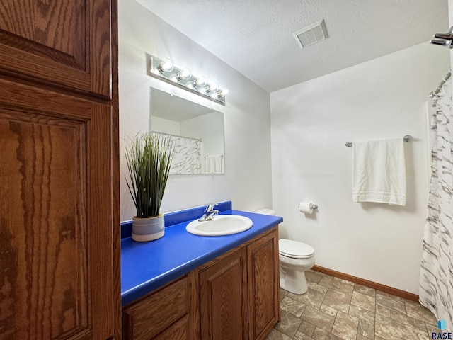 bathroom featuring visible vents, toilet, stone finish floor, a textured ceiling, and vanity