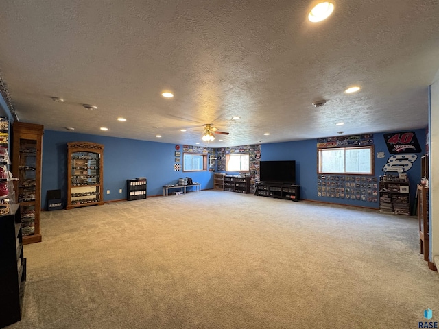 interior space with plenty of natural light, a textured ceiling, a ceiling fan, and carpet flooring