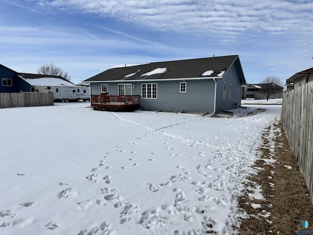 snow covered rear of property featuring fence and a wooden deck