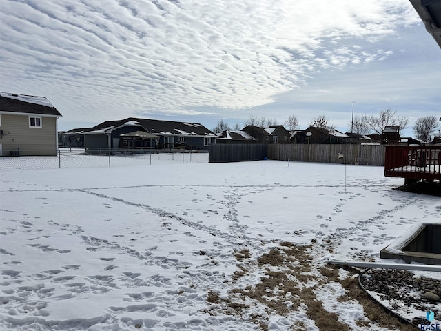 yard layered in snow with a residential view and fence