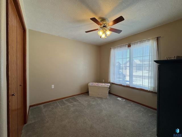 interior space featuring visible vents, baseboards, ceiling fan, carpet, and a textured ceiling