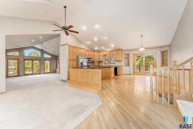 kitchen with stainless steel appliances, open floor plan, and hanging light fixtures