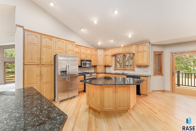 kitchen featuring stainless steel appliances, tasteful backsplash, light brown cabinetry, a kitchen island, and dark stone countertops