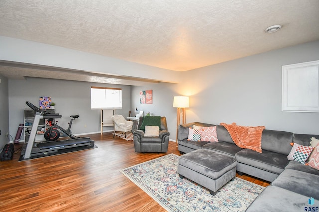 living room with a textured ceiling, wood finished floors, and baseboards