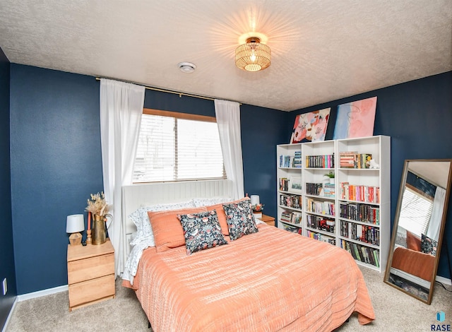 bedroom featuring baseboards, a textured ceiling, and light colored carpet