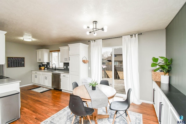 dining area featuring baseboards, a textured ceiling, wood finished floors, and an inviting chandelier