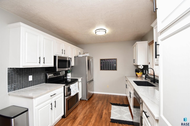 kitchen featuring dark wood finished floors, stainless steel appliances, decorative backsplash, white cabinets, and a sink