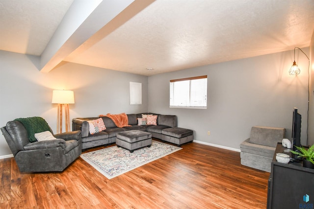 living area featuring a textured ceiling, beam ceiling, baseboards, and wood finished floors