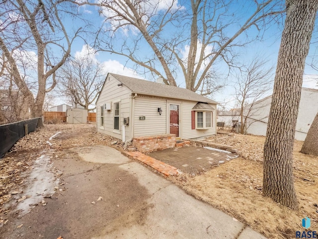 view of front of house featuring an outbuilding, a patio, brick siding, fence, and a shed