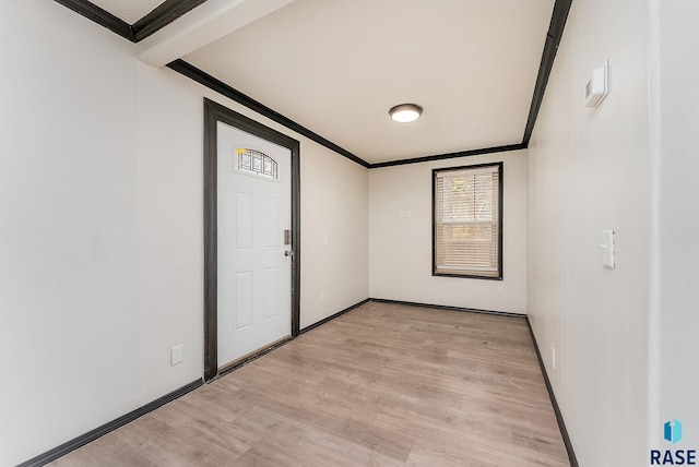 empty room with baseboards, light wood-type flooring, and crown molding