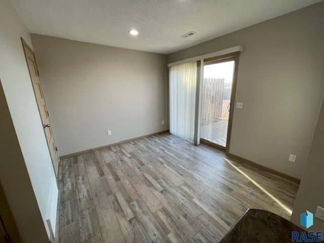 unfurnished bedroom featuring baseboards, visible vents, a textured ceiling, and light wood finished floors