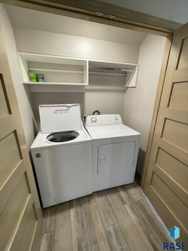 clothes washing area featuring light wood-type flooring, laundry area, and washer and clothes dryer