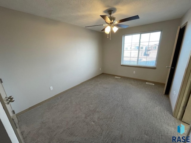 unfurnished bedroom with ceiling fan, baseboards, a textured ceiling, and light colored carpet