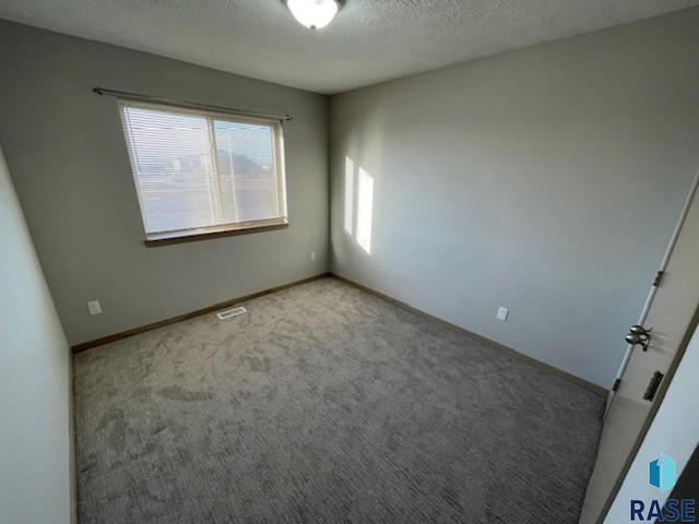 unfurnished room featuring baseboards, visible vents, a textured ceiling, and carpet flooring