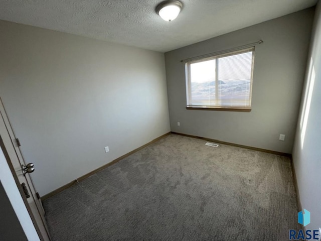 unfurnished room with a textured ceiling, baseboards, visible vents, and light colored carpet