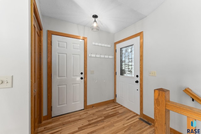 entryway with light wood-type flooring, visible vents, and baseboards