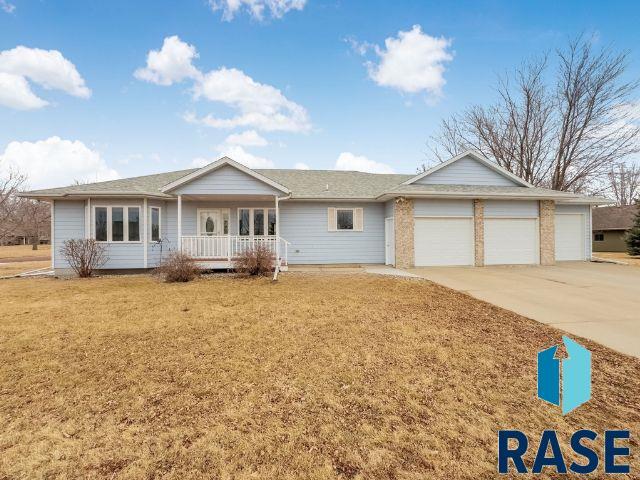 ranch-style house with a garage, driveway, a porch, and a front yard