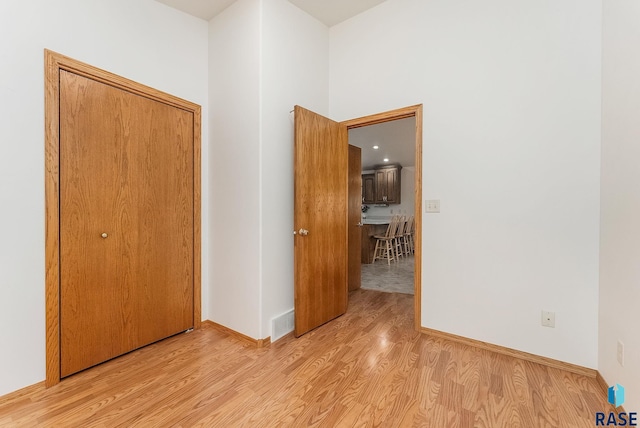 empty room with light wood finished floors, baseboards, and visible vents