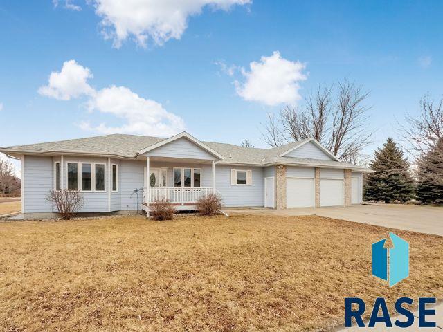 single story home featuring an attached garage, covered porch, concrete driveway, and a front yard