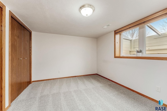 interior space with carpet floors, a textured ceiling, and baseboards