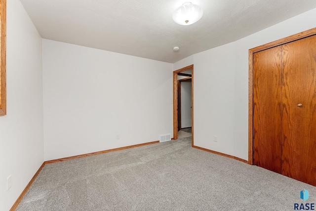 unfurnished bedroom featuring light carpet, baseboards, visible vents, and a closet