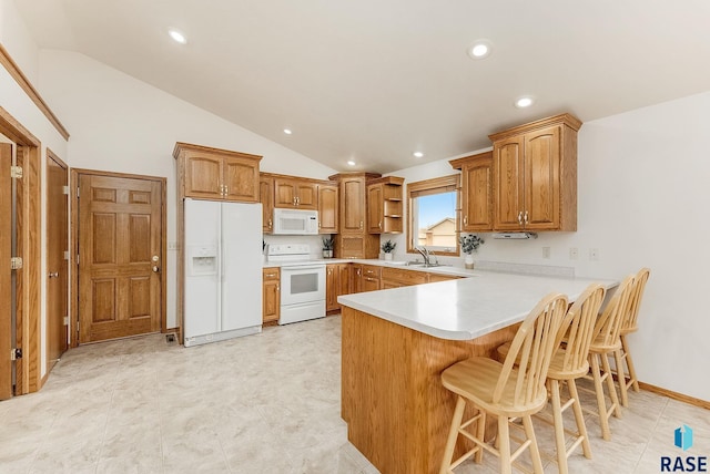 kitchen with brown cabinets, light countertops, a sink, white appliances, and a peninsula