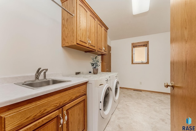 washroom with independent washer and dryer, a sink, cabinet space, and baseboards