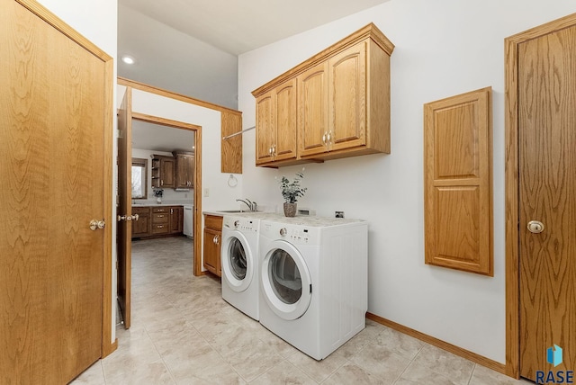 laundry room with cabinet space, a sink, baseboards, and separate washer and dryer